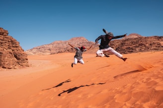 two people jumping in the air in the desert