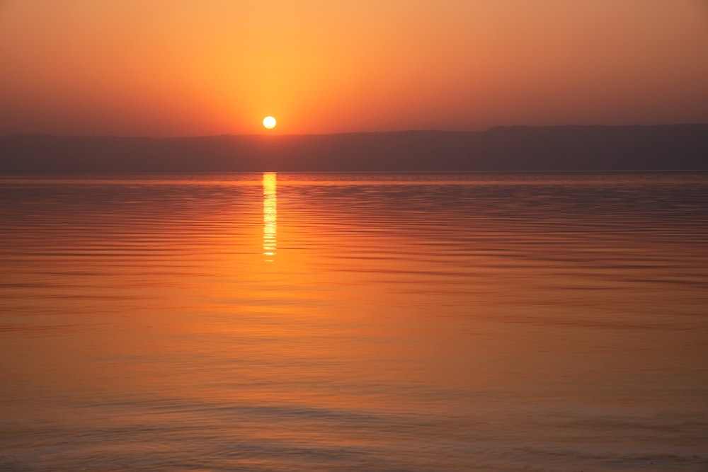 a large body of water with a sunset in the background