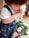 A young child holding a toy Buzz Lightyear figure. The child is wearing a denim-esque jumper with colorful patterns and a white T-shirt. The toy is prominently featured with its green, white, and purple colors.