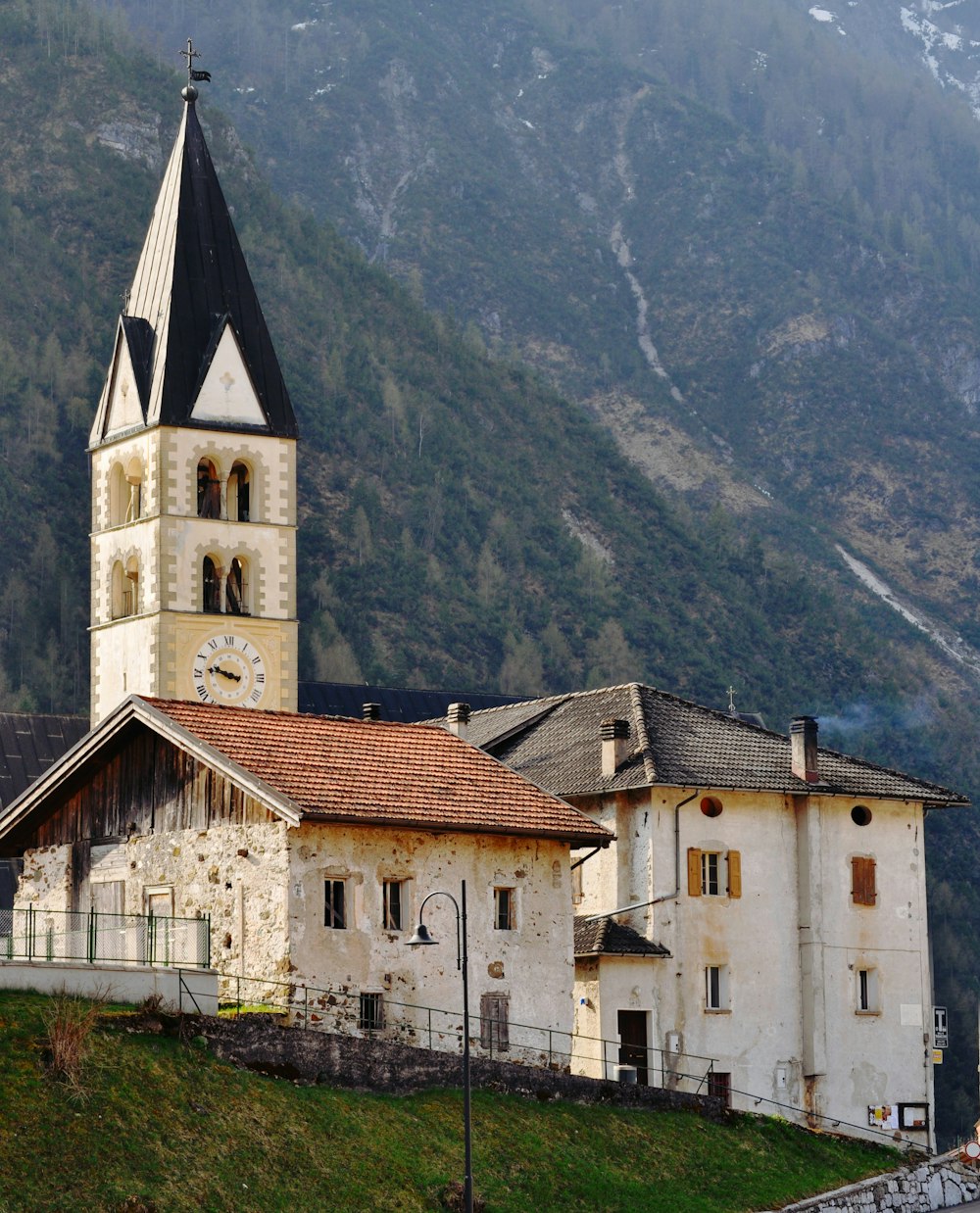 white and brown concrete building near green trees and mountains during daytime