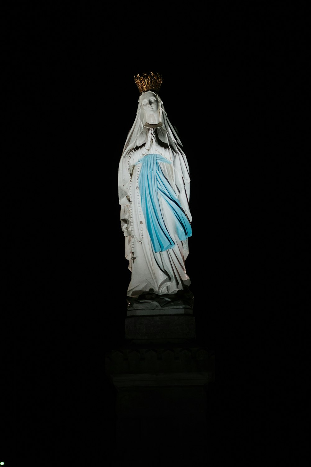 Estatua de la Virgen María sobre superficie negra