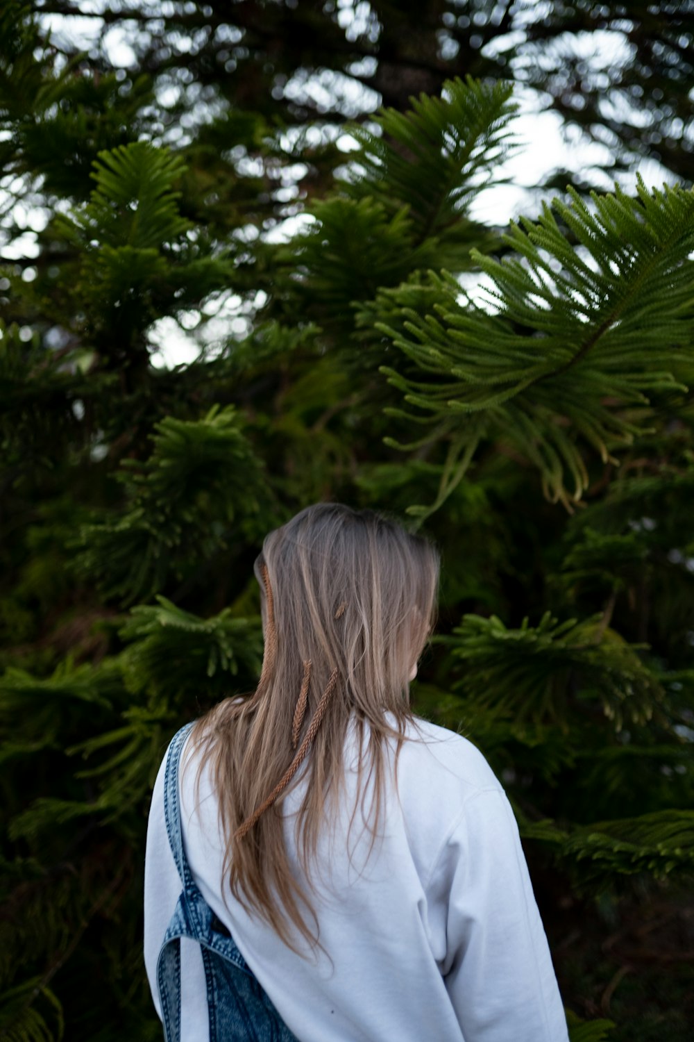 woman in white jacket standing near green tree during daytime