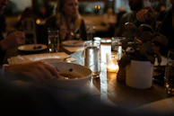 Guests laughing and enjoying their meals in a softly lit dining room.