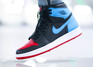 person wearing black blue and white nike air jordan 1 shoes