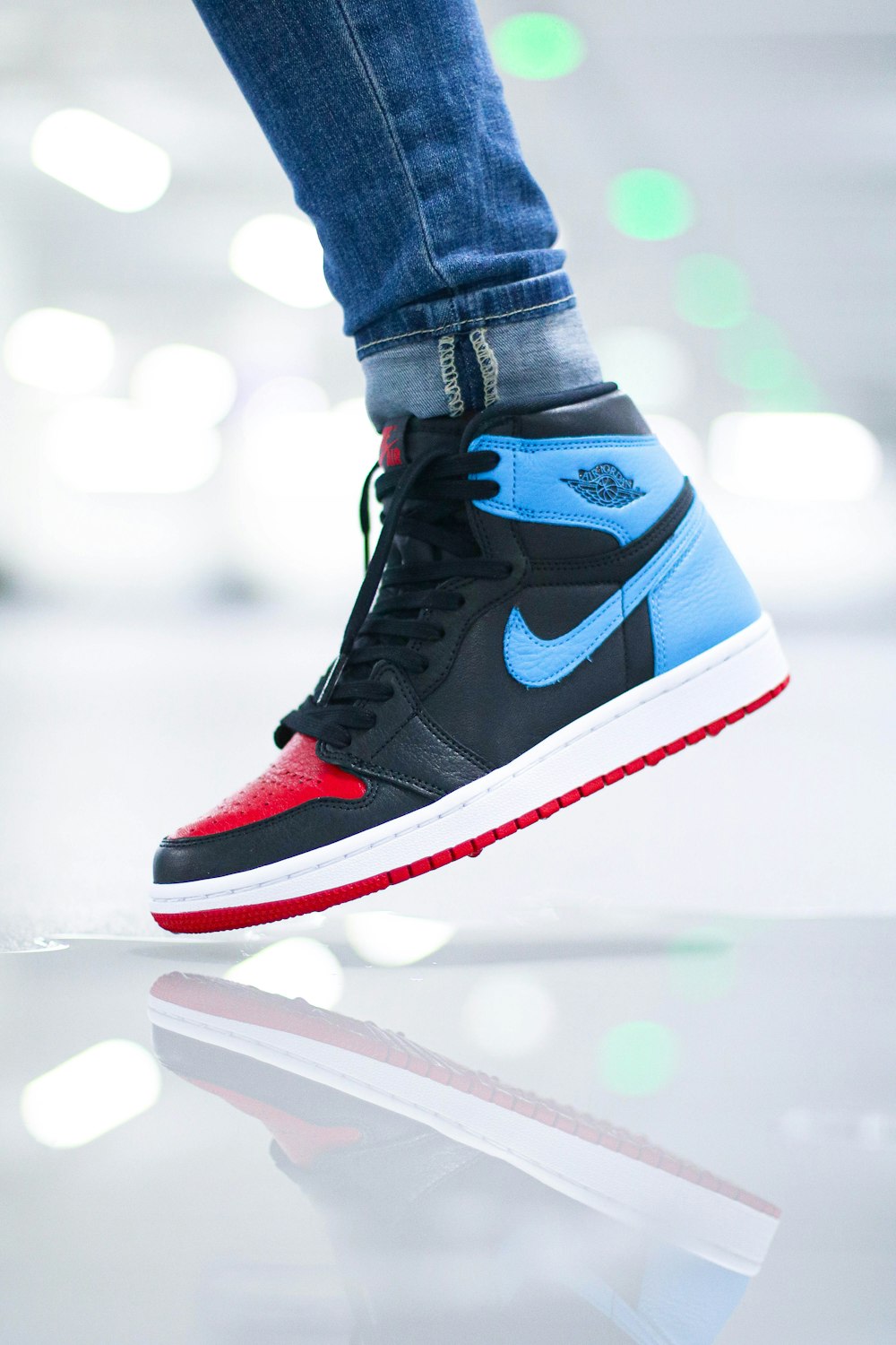 person wearing black blue and white nike air jordan 1 shoes