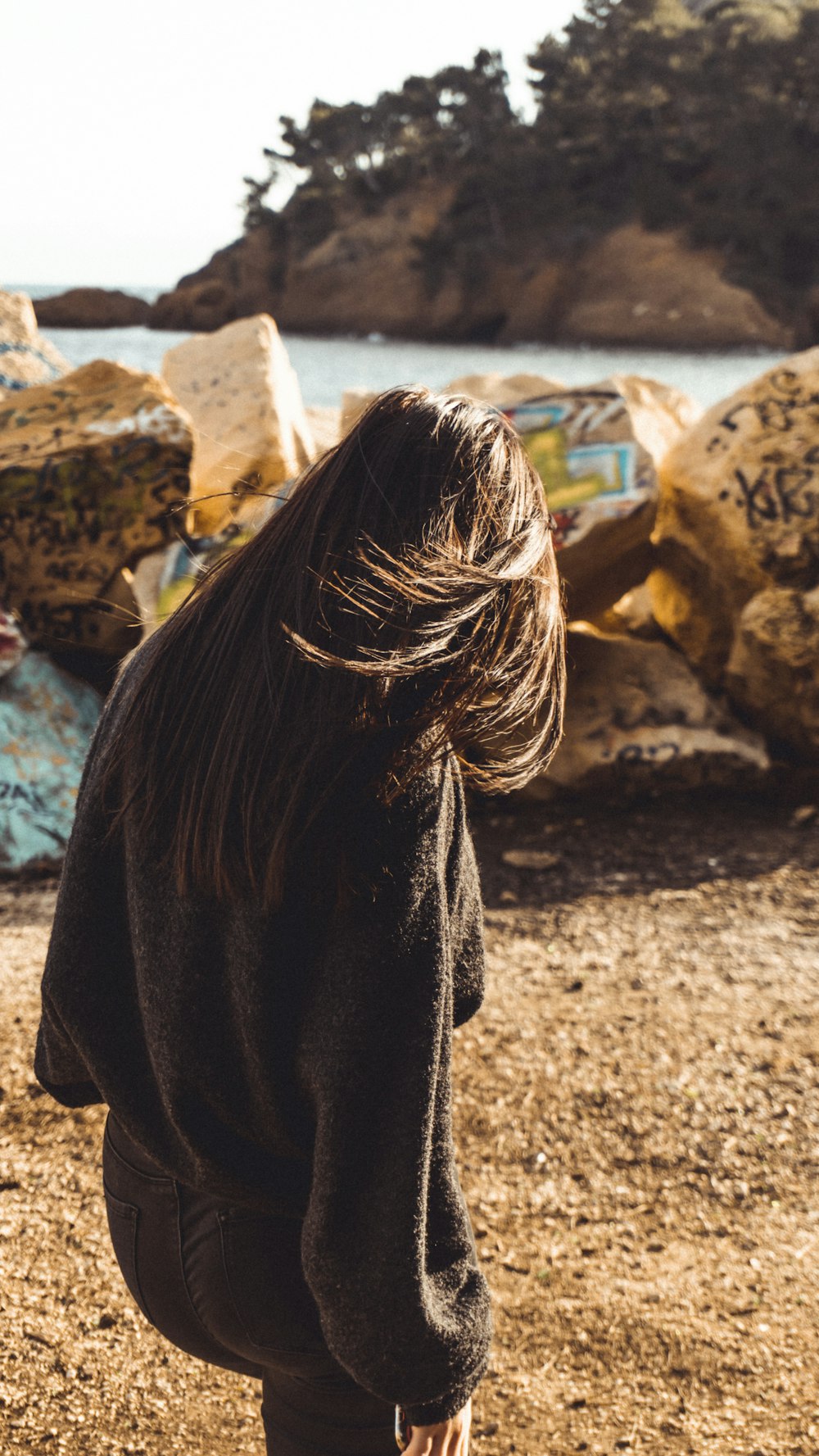 woman in black coat standing on brown rock during daytime