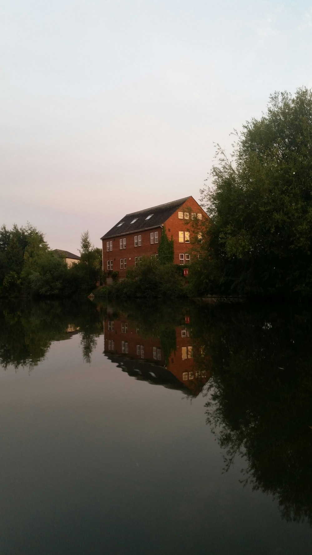 maison brune et noire près des arbres verts et du lac pendant la journée