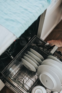 Technician inspecting and repairing an Arçelik dishwasher in a home setting
