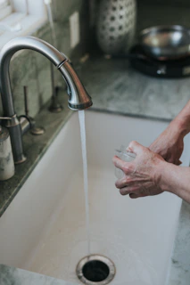 person washing hand on faucet