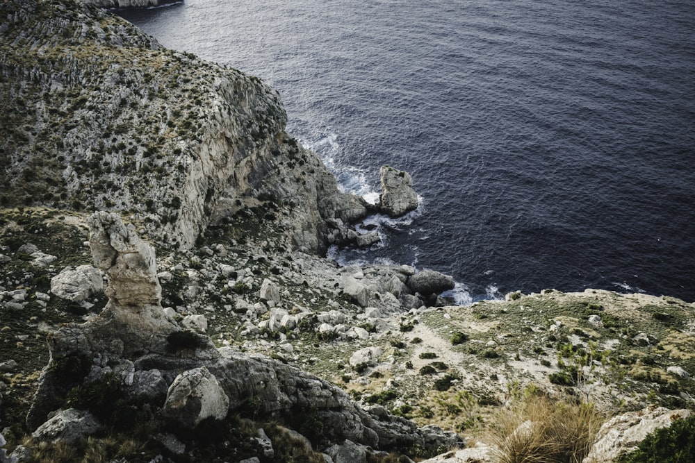 gray rocky mountain beside body of water during daytime