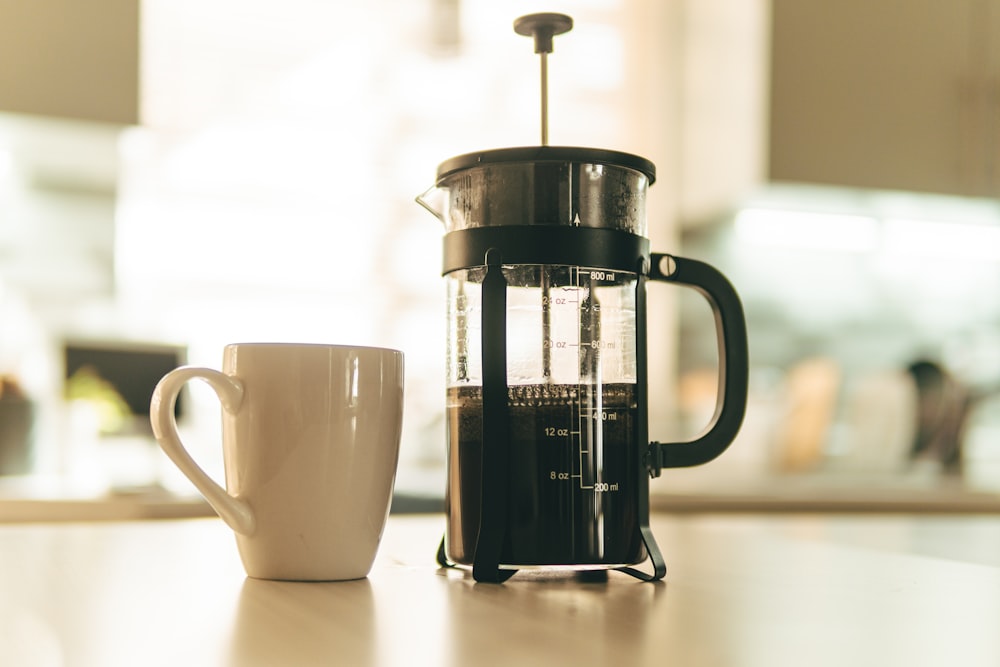 white ceramic mug beside black and white coffee mug