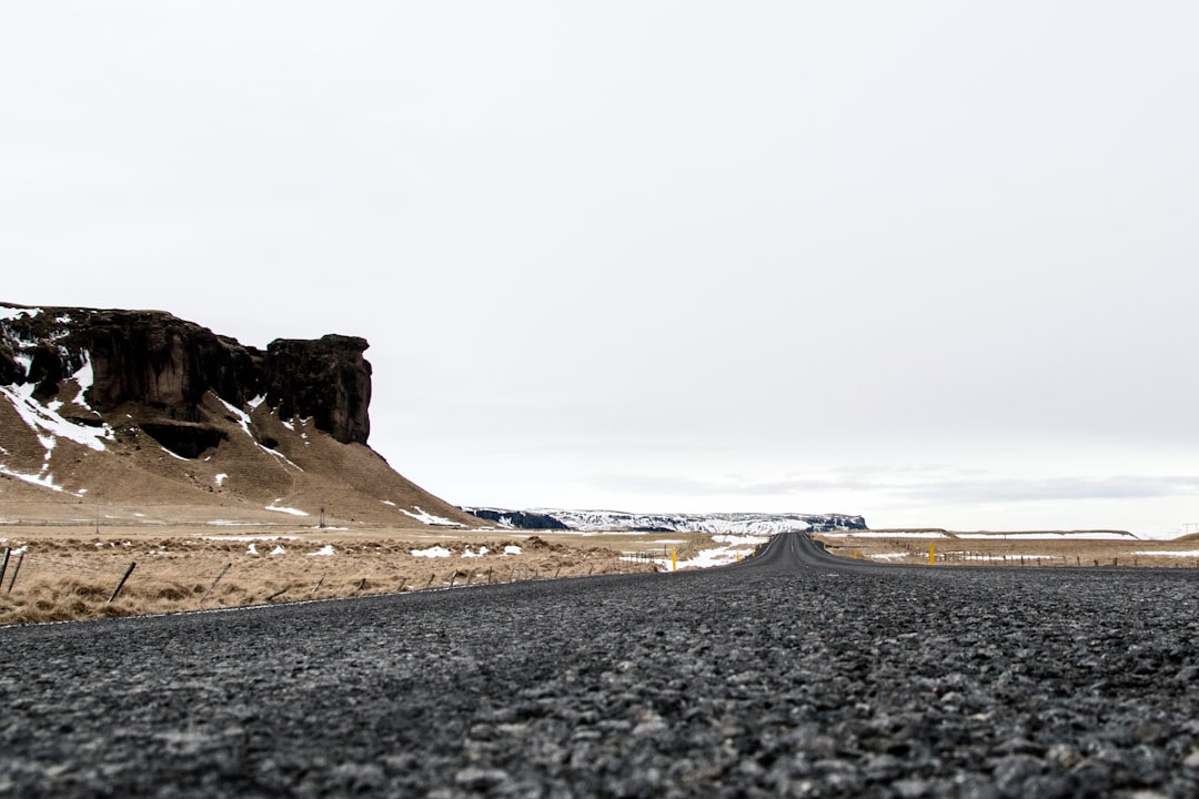 black asphalt road near brown rock formation during daytime