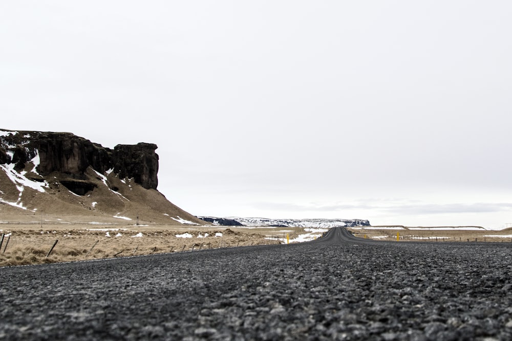 日中の茶色の岩層近くの黒いアスファルト道路