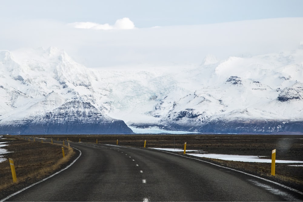 Carretera de concreto gris cerca de la montaña cubierta de nieve durante el día