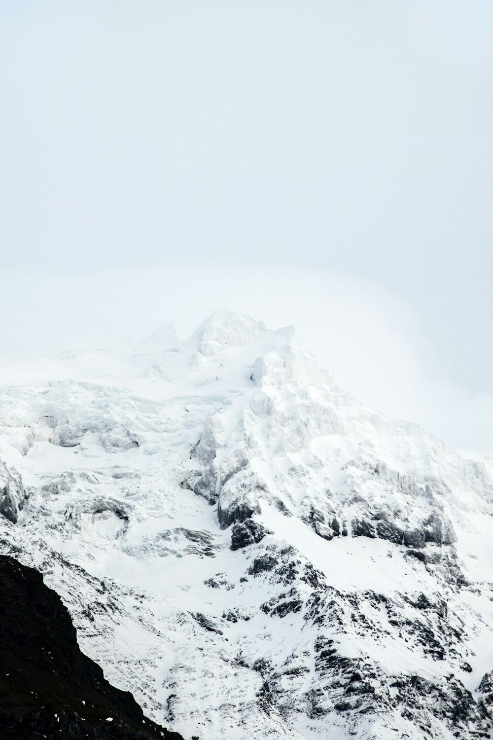Montaña cubierta de nieve bajo el cielo blanco durante el día