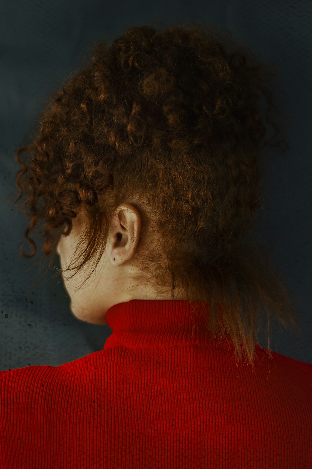 a woman with curly hair wearing a red sweater