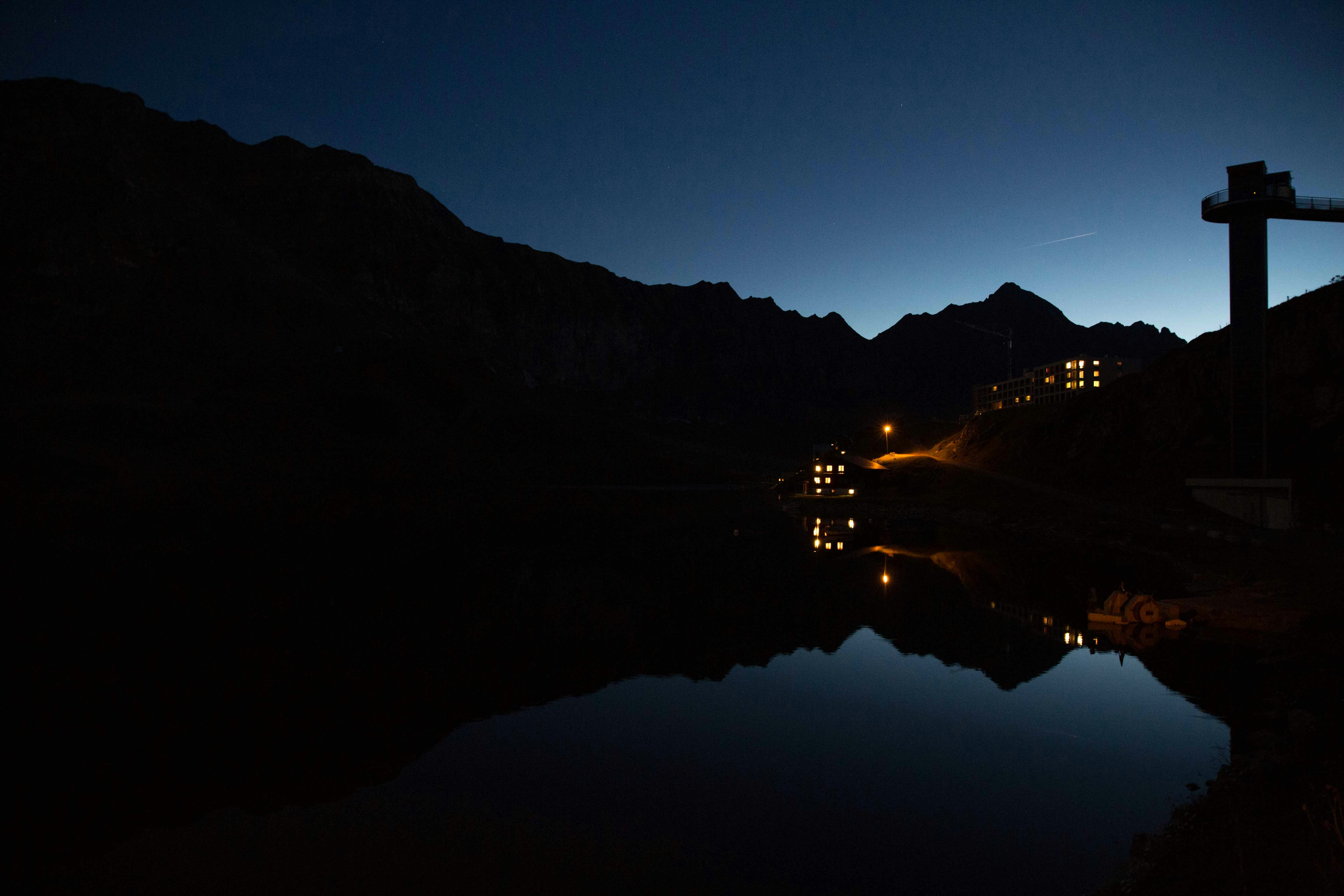 silhouette of mountain near body of water during night time