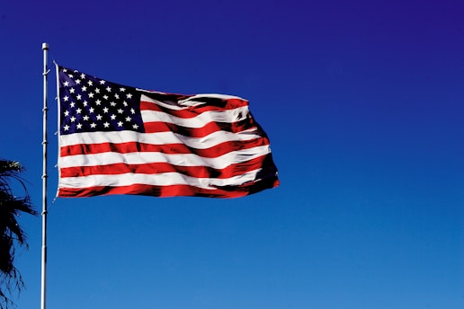 us a flag on pole under blue sky during daytime