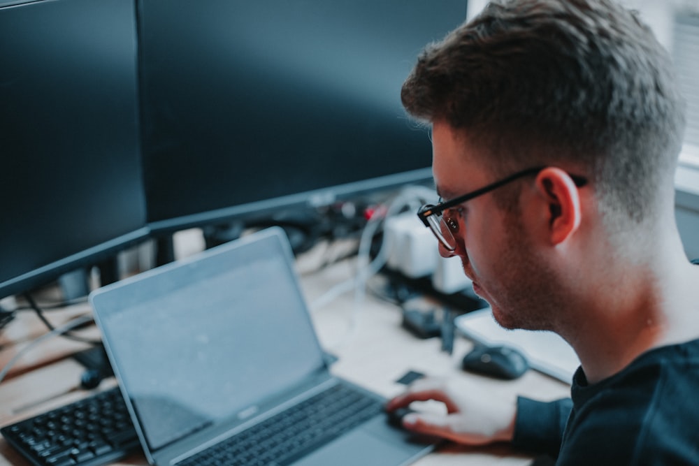 man in black framed eyeglasses using black laptop computer