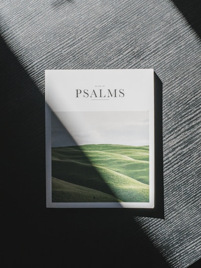 A close-up of the book cover featuring a serene sunrise over a cross on a hill.