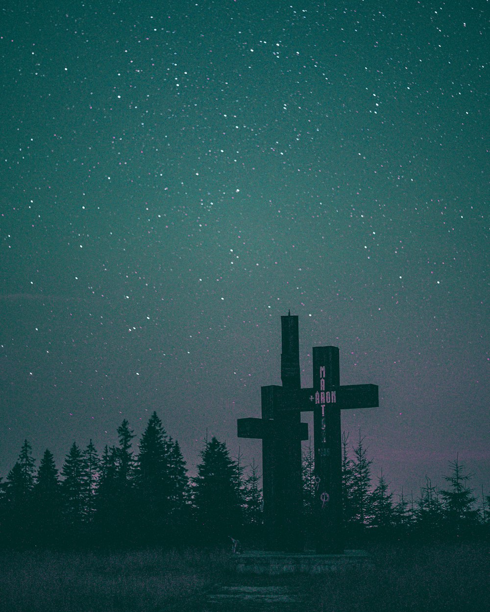 silhouette of cross on forest during night time