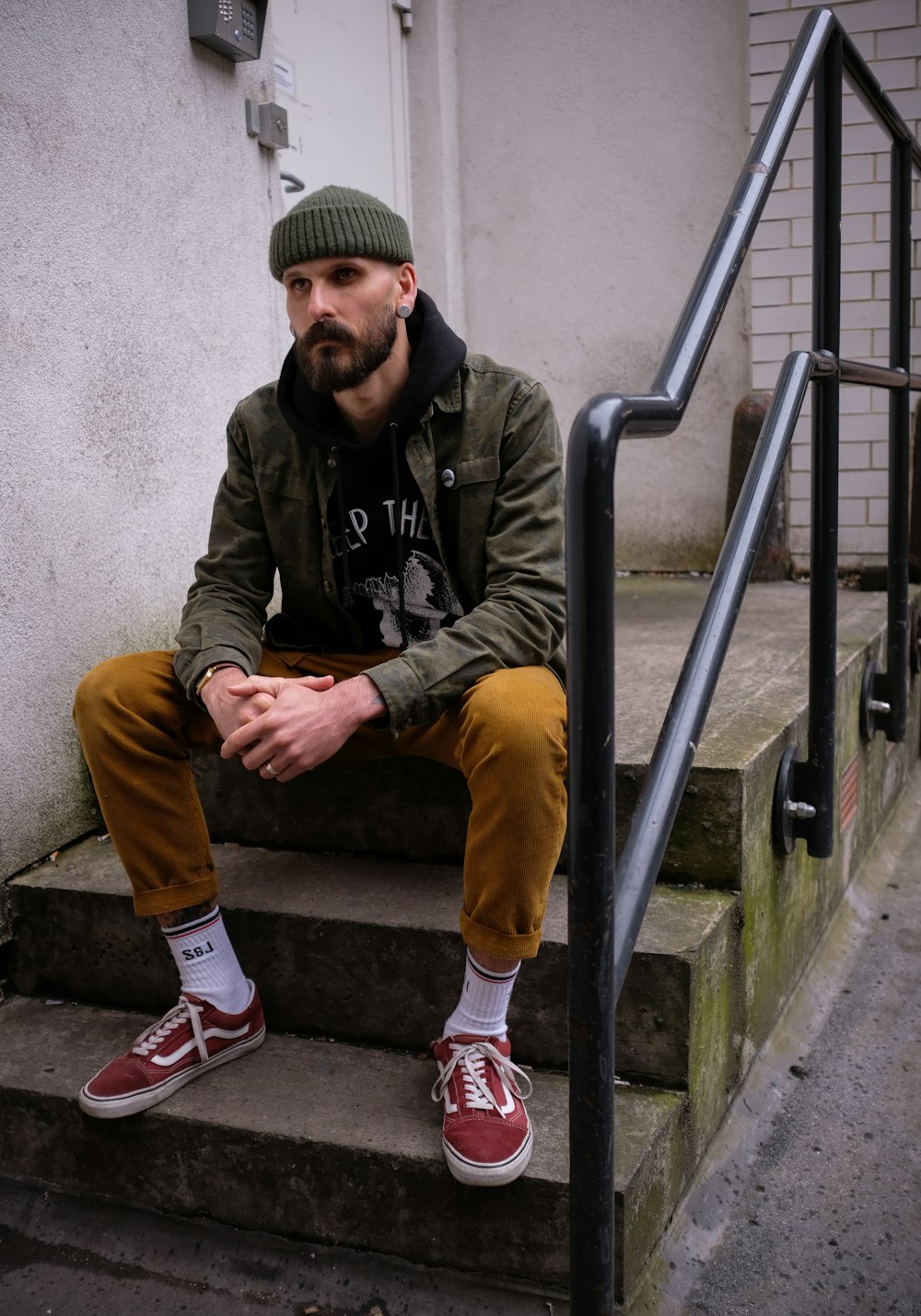 man in gray jacket and yellow pants sitting on stairs