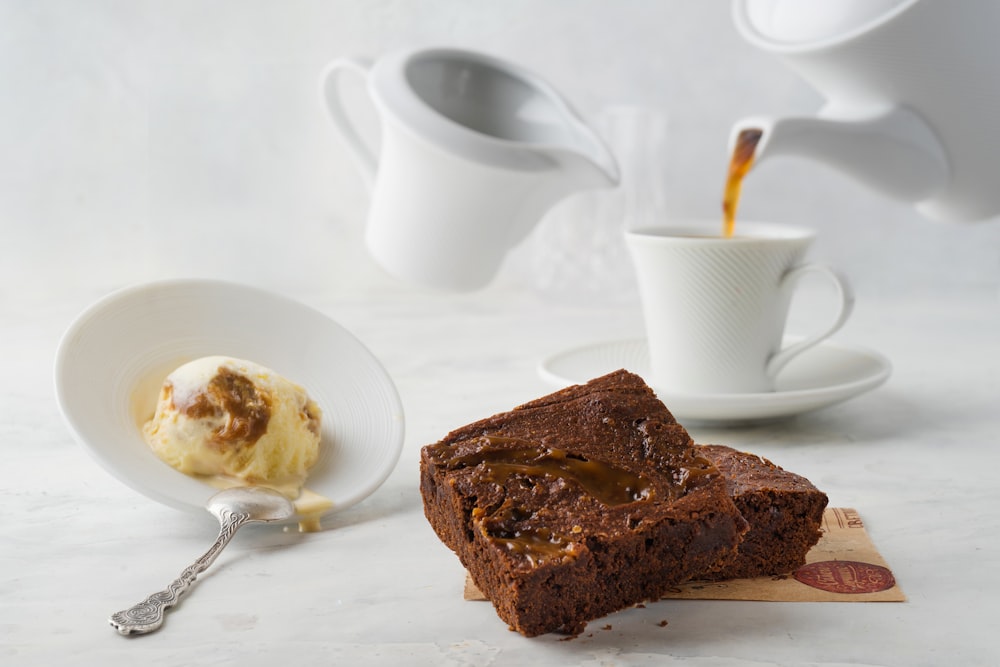 sliced chocolate cake on white ceramic plate beside stainless steel spoon