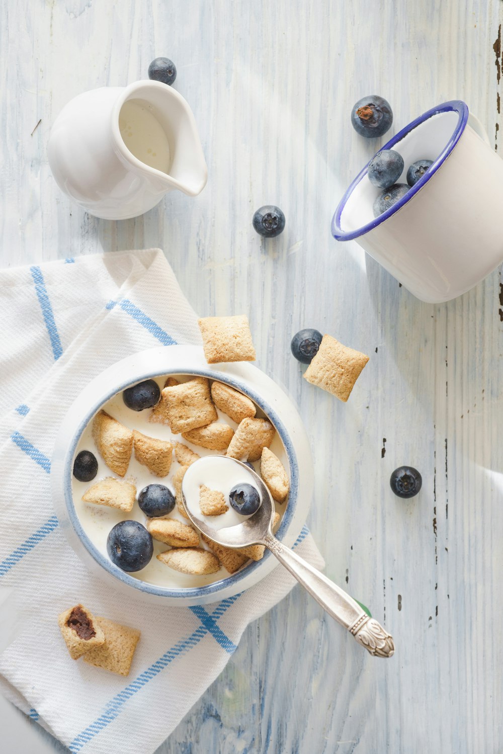 white ceramic mug with stainless steel spoon on white table cloth