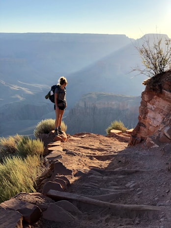 woman in black shirt standing on brown rock formation during daytime