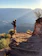 Smiling hiker standing on a rocky overlook with Yellowstone’s Grand Canyon rim in the background.