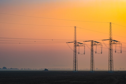 Technicians installing advanced automation hardware on power lines at sunset.