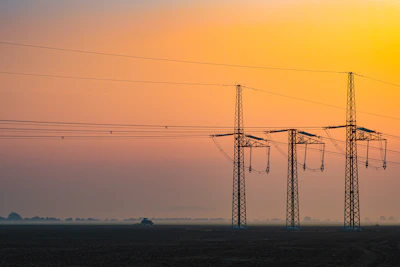 Close-up of high-voltage transmission lines stretching across a rugged African terrain at sunset.
