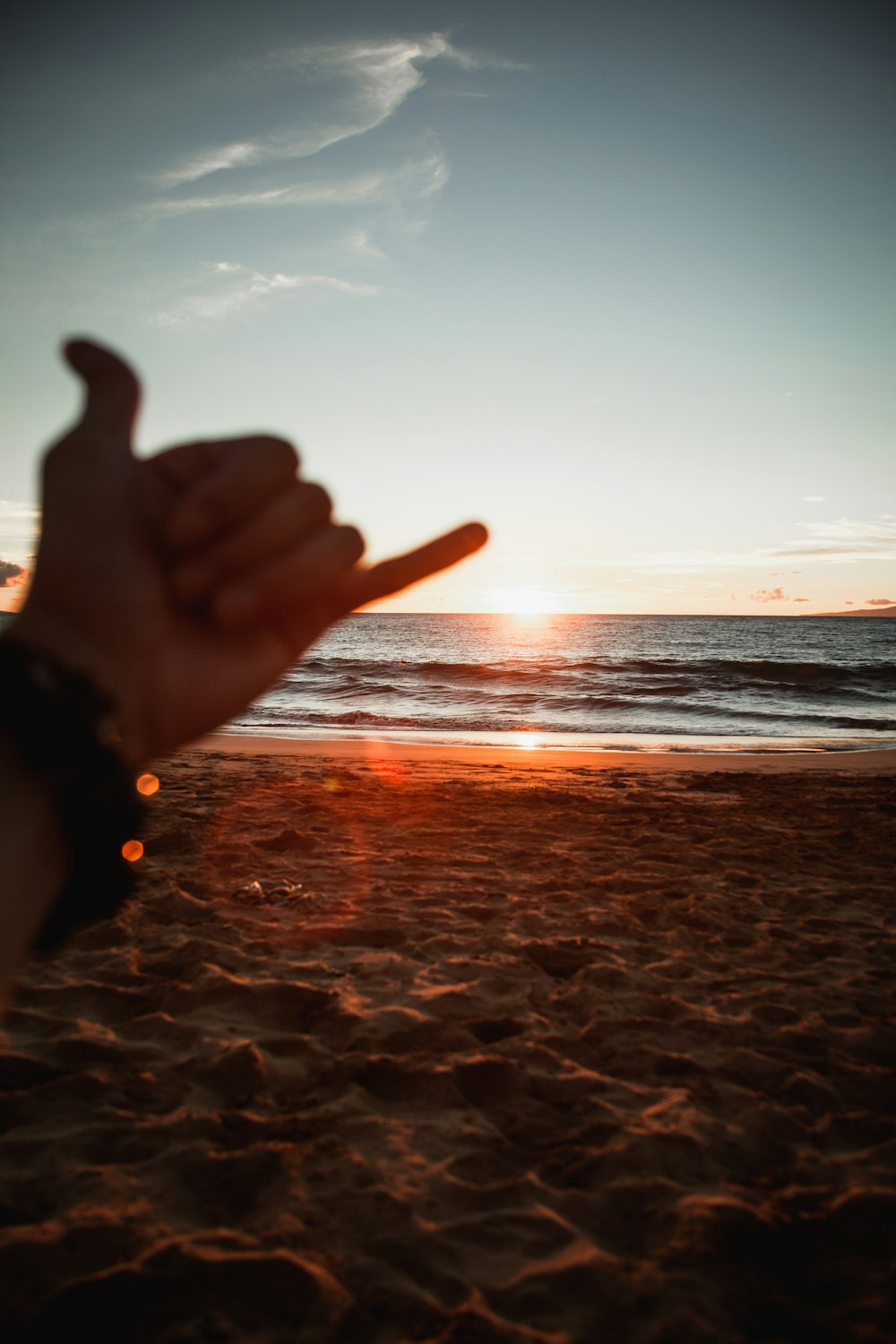 person doing peace sign near sea during sunset