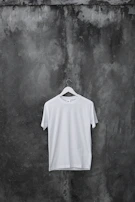 A bright, bold graphic tee displayed on a hanger against a rustic wooden background.