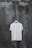 A plain white T-shirt hangs on a wooden hanger against a textured, dark, weathered concrete wall.