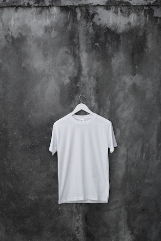 Minimalist casual street t-shirt displayed on a wooden hanger against a plain wall.