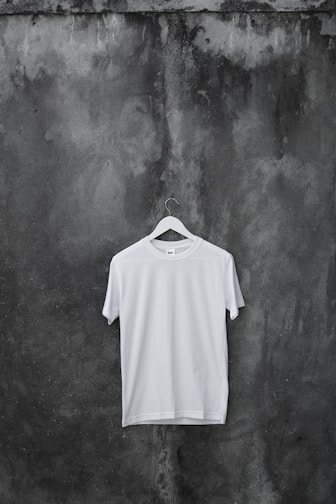 Close-up of a black and red streetwear t-shirt on a hanger against a white wall.