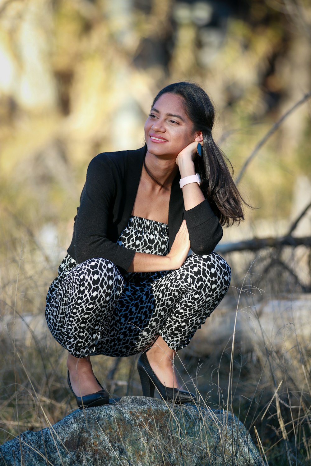 woman in black cardigan and black and white polka dots dress sitting on brown grass during