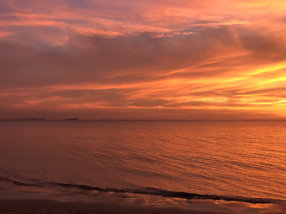 body of water under cloudy sky during sunset