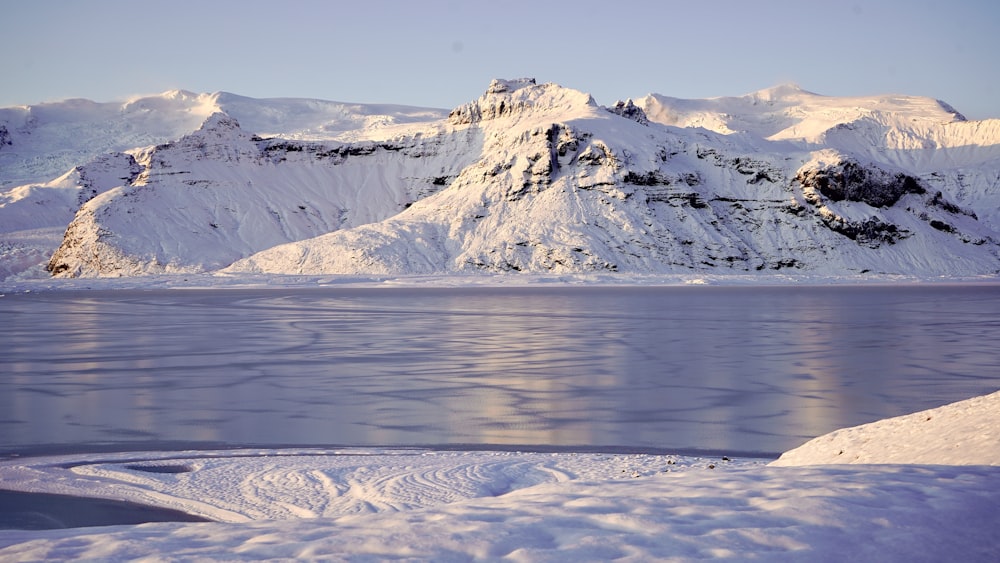 snow covered mountain near body of water during daytime