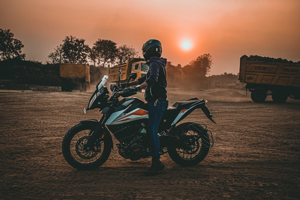 man in black jacket riding black and white sports bike during sunset