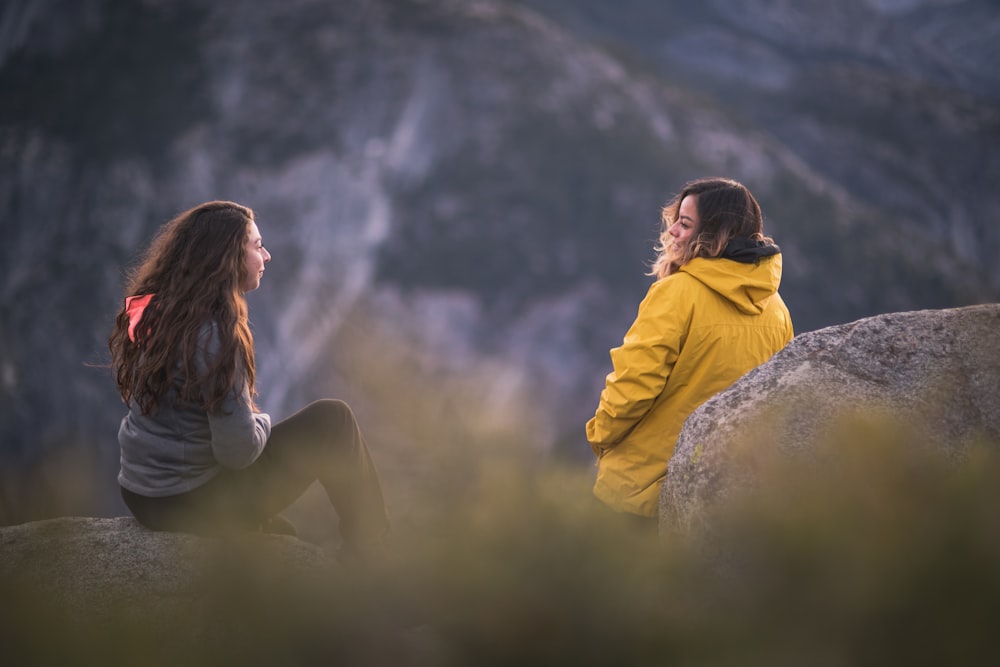 woman in yellow hoodie sitting on green grass during daytime