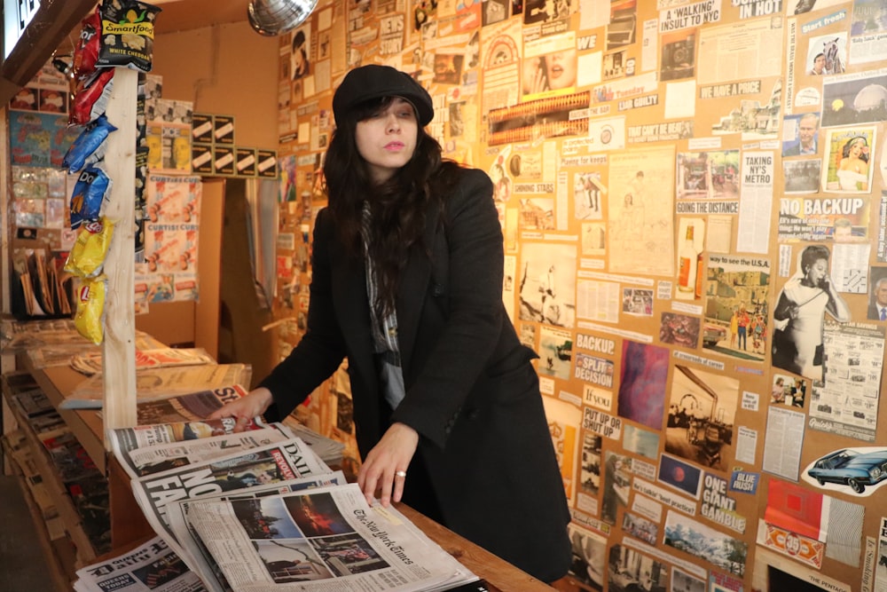 woman in black coat standing near brown wall