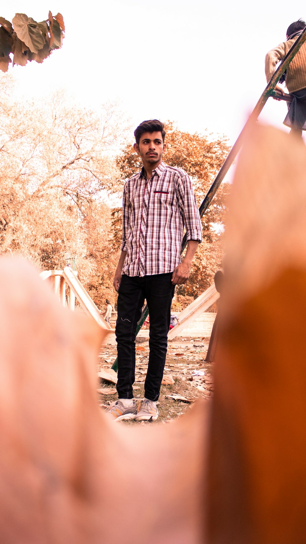 man in black and white plaid dress shirt standing near white metal railings during daytime