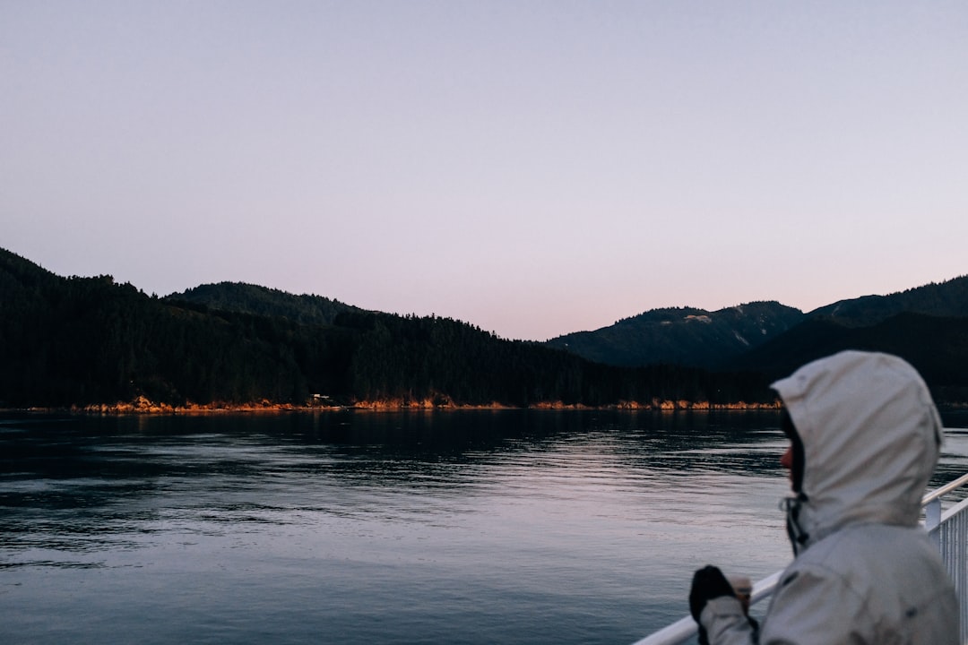 person in white shirt sitting on boat on lake during daytime