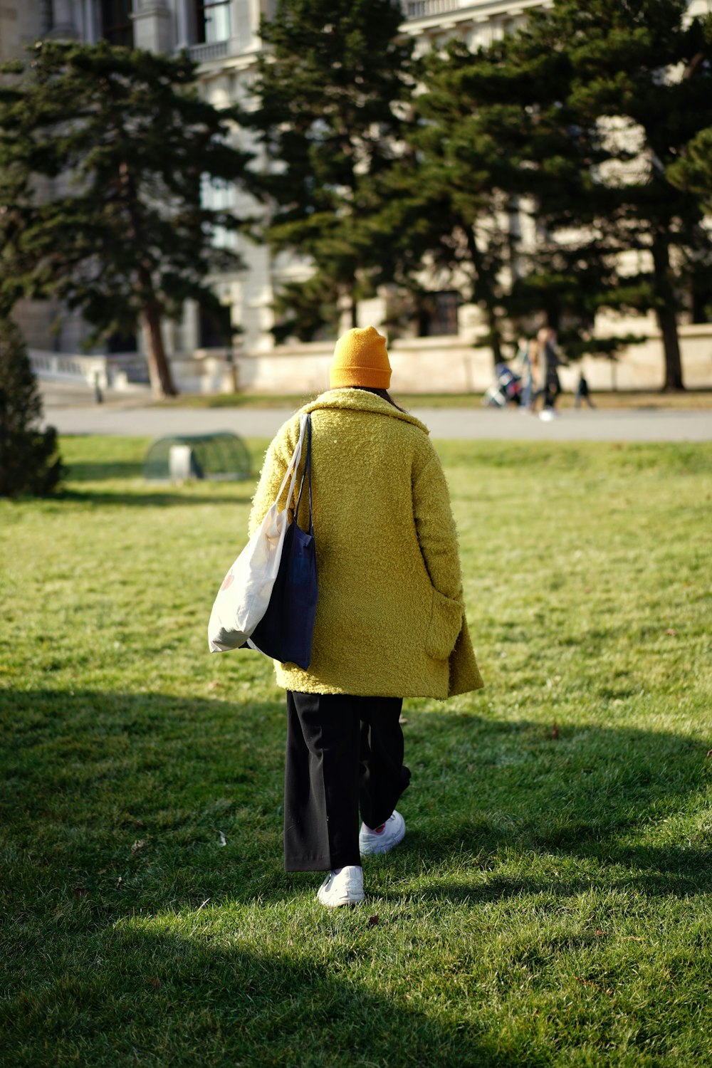 woman in brown coat standing on green grass field during daytime