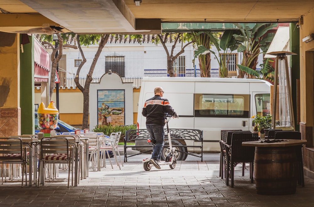 man in black jacket sitting on black metal chair during daytime