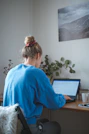 woman in blue sweater sitting in front of laptop computer