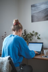 woman in blue sweater sitting in front of laptop computer