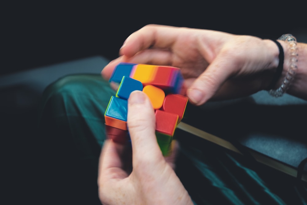 person holding orange green and blue plastic toy